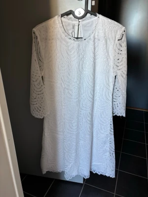 Vit examensklänning i spets - Helt ny klänning från Only, perfekt för skolavslutning eller examen! Säljer på grund av att jag beställde olika alternativ och valde en annan! Det är en vit klänning med vackert spetsmönster och trekvartsärmar. Klänningen har rund halsringning, rak passform och fina vågiga kanter vid ärmslut och nederkant.