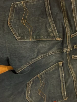 Blå slitna jeans med broderade fickor - Säljer ett par blå jeans med slitningar och snygga broderade detaljer på bakfickorna. Köpte jeansen i Prag för 2,100 men säljer dem för 700