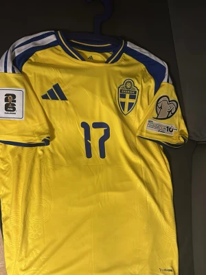 Sverige matchtröja Gyökeres #17 -  Sverige matchtröja med Gyökeres och nummer 17 på ryggen. Tröjan har FIFA och Foundation 10 patchar på ärmarna, samt det svenska landslagets emblem på bröstet. Storlek L och har aldrig använts innan 