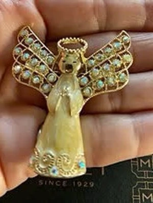 Monet Vintage änglabrosch i guld och pärlemor 5cm stor - Unik brosch formad som en ängel med skimrande pärlemor och guldfärgade detaljer. Vingarna är dekorerade med små gnistrande stenar i vitt och blått. Monet sin e 1929 ängel brosch i guldpläterat material för unisex. Broschen föreställer en ängel med utbredda vingar dekorerade med ljusa stenar. Hög 5cm. Framsidan har en ljus, pärlemorskimrande klänning av emalj och detaljerad utformning av huvud, gloria och vingar. Baksidan är helt guldplätera