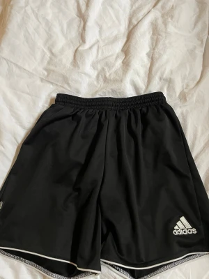Svarta Adidas shorts - Svarta sportiga shorts från Adidas. Elastisk midja för skön passform. Perfekta för träning. De är som nya!