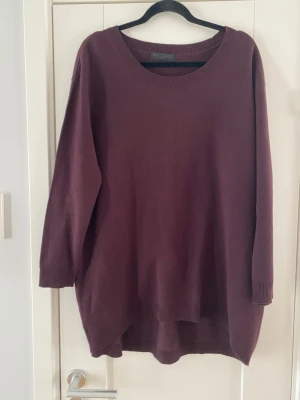 Vinröd oversized stickad tröja - Mysig vinröd stickad tröja i oversized modell med rund halsringning och långa ärmar. Tröjan har ribbade muddar vid ärmslut och nederkant samt en något längre bakdel för en avslappnad look. Perfekt för lager på lager och chill dagar. Vinröd längre stickad tröja med 3/4 ärm i strl S/M fr Movesgood. Tröjan är längre där bak.  Sparsamt använd och i fint begagnat skick   Mått Över bröstet: ca 67 cm Längd från axeln och ner: ca 80 cm  Viskos, nylon och kashmir  Kommer från ett djur och rökfritt hem