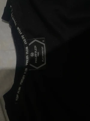 Svart sweatshirt  - Snygg svart sweatshirt med guldfärgat logotryck på bröstet. Tröjan har rund halsringning och långa ärmar.. Perfekt för dig som gillar  streetwear-plagg.