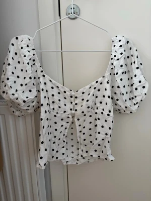 Prickig topp - Jättegullig prickig topp med knappar och öppen nertill, storlek XS.