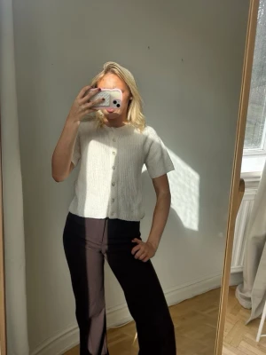 Vit ribbad kofta med kort ärm💖💖 - Kortärmad vit kofta med ribbad struktur och rund hals. Koftan har knappar framtill och är gjord i ett mjukt, stickat material som ger en avslappnad men ändå stilren look. Perfekt att matcha med både jeans och kjol.