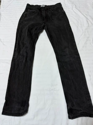 Svarta raka jeans från 157 - Säljer ett par svarta jeans från 157 med rak passform och klassisk femficksdesign. Jeansen har en enkel look och är tillverkade i ett slitstarkt denimtyg. Perfekta för dig som gillar en clean och tidlös stil.