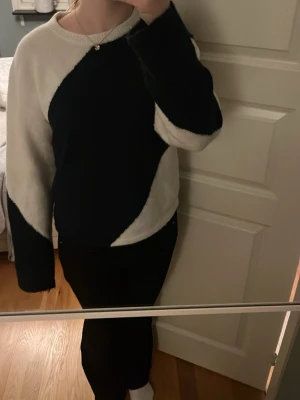 Svartvit stickad tröja med mönster - Säljer en snygg stickad tröja i mörkblått och vitt med ett coolt, diagonalt mönster. Tröjan har långa ärmar och en avslappnad passform, perfekt för dig som gillar en trendig och bekväm stil. Materialet ser ut att vara mjukt och värmande. Den är lite nopprig 