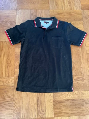 Vintage piké från dressman - Snygg och sällsynt vintage piké tröja från Dressman. Snygg svart färg med rödvita detaljer. Väldigt skön och bra passform Storlek M. Mycket bra skick inga defekter. Skriv vid eventuella funderingar😁