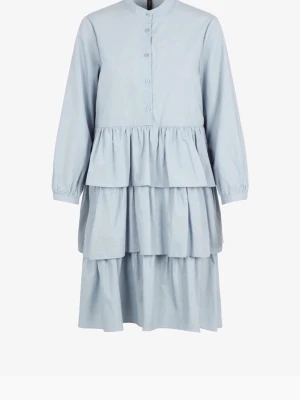 Ljusblå volangklänning med knappar - Supersöt ljusblå klänning med volanger och knappar framtill. Klänningen har lång ärm och v-ringad hals, samt flera lager i kjolen som ger en fluffig look. Tillverkad i bomull för en skön känsla. Perfekt för dig som gillar romantisk och trendig stil.