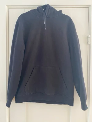 Svart hoodie med magficka S - En klassisk svart hoodie med stor magficka och justerbar huva med dragsko. Hoodien har ribbade muddar vid ärmslut och nederkant. Perfekt för en avslappnad och stilren look. Materialet känns mjukt och bekvämt.   Lite nopprigt i övrigt i bra begagnat skick   Mått Över bröstet: ca 53 cm Längd från axeln och ner: ca 67 cm  60% bomull och 40% polyester   Kommer från ett djur och rökfritt hem 