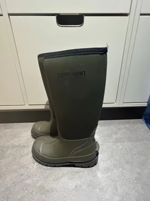 Jakt/allväder stövlar från Engelsons - Säljer ett par gröna höga stövla/Euro-Hunt. De är tillverkade i slitstarkt gummimaterial med grov sula för bra grepp och har en mjuk kant upptill likt allväderstövlar. Oanvända!