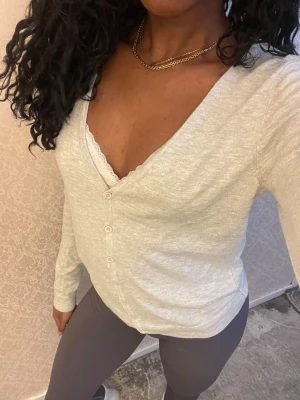 Ljusgrå cardigan med v-ringning - Ljusgrå cardigan med djup v-ringning och knäppning framtill. Tillverkad i ett tunt, mjukt material som känns skönt mot huden. Långa ärmar och enkel, stilren design som passar till mycket. Perfekt att slänga över ett linne eller t-shirt.