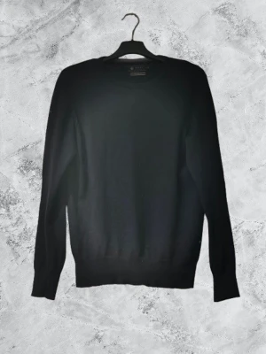 Svart stickad tröja från Riley - En stilren svart stickad tröja från RileyTröjan har rund halsringning, långa ärmar och ribbade muddar vid ärmslut och nederkant. Perfekt basplagg för lager på lager och funkar till det mesta i garderoben.