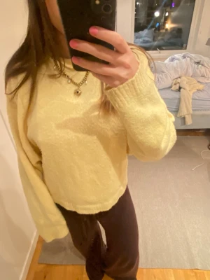Gul stickad tröja - Mysig gul stickad tröja med oversized passform och långa ärmar. Tröjan har ribbade muddar vid ärmslut och nederkant. Perfekt för lager på lager och ger en avslappnad look. Materialet ser mjukt och fluffigt ut.