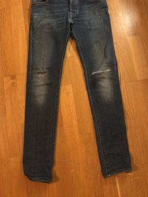 Mörkblå skinny jeans med slitningar - Säljer ett par mörkblå skinny jeans från jacob cohen med snygga slitningar vid knäna och klassiska fem fickor. Jeansen har en smal passform och är tillverkade i stretchigt denimtyg för extra komfort. Perfekta för dig som gillar en trendig och avslappnad stil.