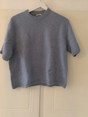 Ljusblå stickad t-shirt - Säljer denna top från Gina då den ej kommer till användning längre och bara ligger i garderoben. 