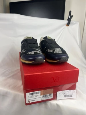 Valentino Rockrunners - Snygga sneakers från Valentino i modellen Rockrunner Mesh. Skorna är svarta med vita detaljer och har en klassisk låg siluett. Ovandelen är i mesh och läder, vilket ger både stil och komfort. Perfekta för dig som vill ha en exklusiv touch på din outfit.