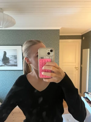 Svart V-ringad tröja - En stilren svart tröja med V-ringning och långa ärmar. Perfekt basplagg som är lätt att matcha till olika outfits. Tröjan har en enkel och klassisk design utan synliga mönster eller detaljer.