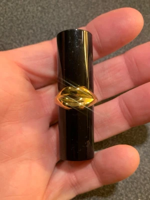 Rött läppstift från Pat McGrath  - Snyggt rött läppstift i svart hylsa med unik guldfärgad dekor i form av läppar runt mitten. Läppstiftet har en klassisk rundad form och hylsan är tillverkad av plast och metall. Perfekt för dig som vill ha en statement-accessoar i sminkväskan. Mini storlek 