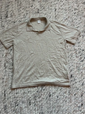 Beige piké med krage - En enkel beige pikétröja med klassisk krage och korta ärmar. Tillverkad i mjukt bomullsmaterial som känns skönt mot huden. Perfekt för en avslappnad och stilren look.