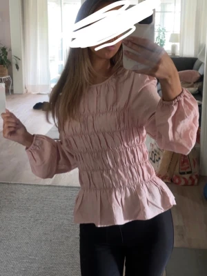 Ljusrosa blus med volang - Supersöt ljusrosa blus från Nelly💕använd endast ett fåtal gånger🙌🏼 det är stl XS men har resår runt hela så passar säkert till flera storlekar💕