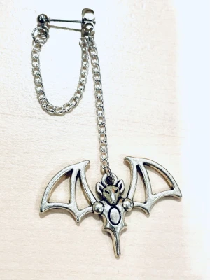 By prisförslag- 1 st Silvrigt örhänge med fladdermus - Unikt örhänge i silverfärgad metall med en kedja och en stor fladdermusberlock. Fladdermusen har detaljerade vingar och ett coolt, edgy uttryck. Perfekt för dig som gillar alternativ stil och vill sticka ut med dina accessoarer.