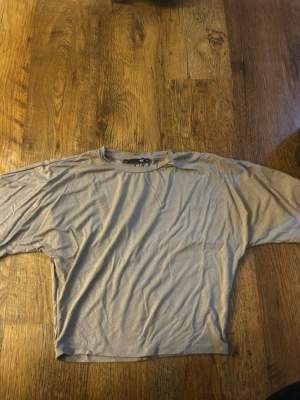 Beige croppad t-shirt - En enkel beige croppad t-shirt med rund hals och korta ärmar. Tillverkad i mjukt material som känns skönt mot huden. Perfekt till jeans eller kjol för en avslappnad look. Använd en gång