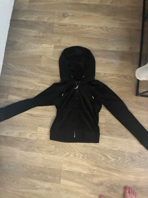 Svart hoodie från Juicy Couture - Snygg svart hoodie från Juicy Couture med dragkedja framtill och justerbar huva med snören. Denr tvättad en gång använd några gånger men fortfarande som ny i tyget. JAG HAR MATCHADE BYXOR PÅ MIN PROFIL