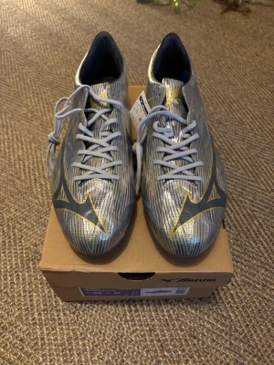 Mizuno Alpha II Elite AG fotbollsskor - Säljer pga fel storlek (nypris 2299kr). En otrolig speedboot för spel på konstgräs, läs mer om skorna här:  https://www.stadium.se/sport/fotboll/fotbollsskor/399653101109/mizuno.mizuno-ii-elite-ag.galaxy-silver?gclsrc=aw.ds&gad_source=1&gad_campaignid=22364513701&gbraid=0AAAAAD4Z7V-B5J_9pbP-1x_AwafxV48Nl&gclid=CjwKCAjwgajSBhBEEiwASicJU7X3B9M4102Lq_TrStuzjck8d4ovP6Ot2U2LmIgDMlmJGjGhqFXD6xoCP50QAvD_BwE
