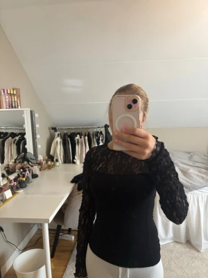 Svart långärmad spetsblus - Säljer en svart långärmad blus med spets upptill och på ärmarna. Toppen har en tight passform och rund halsringning. Perfekt för dig som vill ha en elegant och trendig look. Denna tröjan passar till allt en riktig snygg vardags tröja men även en fest topp!!😍😍😍
