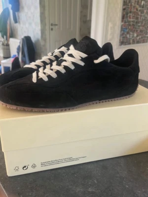 Svarta arigatos - Snygga svarta sneakers i mocka med vita skosnören och gummisula. Låg modell med stilren design och diskreta detaljer. Perfekta för dig som gillar en clean och klassisk look till vardagsoutfiten. Säljer då jag glömde lämna tillbaka dem på Mintoo. Kvitto ingår 