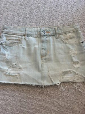 Ljus jeanskjol från Abercrombie & Fitch - Säljer en ljusblå kort jeanskjol från Abercrombie & Fitch med slitna detaljer och fransig nederkant. Kjolen har klassiska fickor fram och bak samt knapp och dragkedja framtill. Perfekt för en avslappnad och trendig look.💓