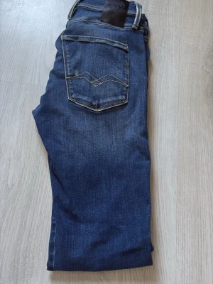 Blå slim fit jeans med fem fickor - Snygga blå slim fit jeans med klassisk femficksdesign och lätt slitning på låren. Jeansen har normal midja och smala ben, perfekta till vardagslooken. Tillverkade i denim med stretch för extra komfort.