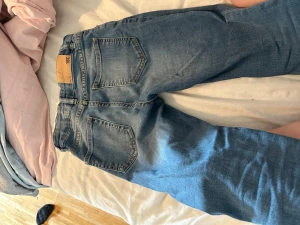 Blå raka jeans med klassisk passform - Snygga blå jeans med raka ben och klassisk femficksmodell. Jeansen har normalhög midja, bälteshällor och knappgylf. Perfekta för en avslappnad och trendig look. Materialet är mjukt och följsamt för extra komfort.