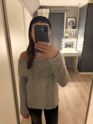 Ljusgrå off shoulder stickad tröja - Trendig ljusgrå stickad tröja med off shoulder-design och bred ribbad kant upptill. 