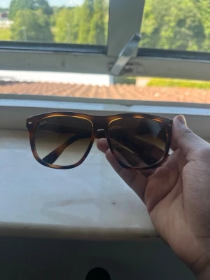 Bruna Ray-Ban solglasögon Boyfriend - Snygga solglasögon från Ray-Ban i klassisk boyfriend-modell med brunmelerat mönster på bågarna. Glasen är mörka och ger en cool look, perfekt för soliga dagar. Stilsäkra och tidlösa accessoarer som lyfter din outfit.