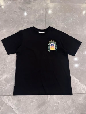 Svart Casablanca t-shirt  - Snygg svart t-shirt med färgglatt tryck från Casablanca på bröstet och stort motiv på ryggen. T-shirten har rund hals och korta ärmar. Perfekt för dig som vill ha en unik och trendig look.