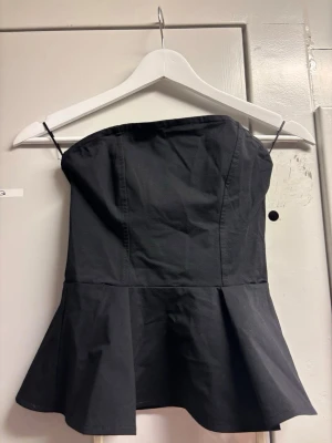 Svart axelbandslös peplum tubtopp - Tubtopp från hm, knappt använd! Super söt topp!