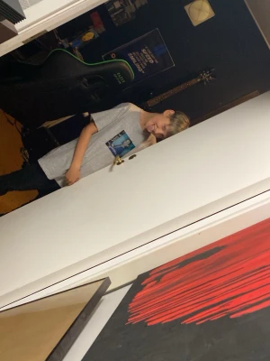 Rasmus 12 år från Västerås  - En grå t-shirt i bomull med ett tryck på bröstet som föreställer ett motiv i blått och vitt. T-shirten har korta ärmar och rund hals. Perfekt för en avslappnad stil.