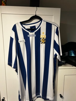 IFK Göteborg matchtröja blåvit - Säljer en officiell IFK Göteborg matchtröja från Craft i storlek XXL. Tröjan har klassiska blå och vita vertikala ränder, broderat klubbmärke med guldstjärna och sponsorloggor. Tillverkad i lätt och ventilerande material, perfekt för fotboll eller träning. Storlek XXL men funkar bra för L