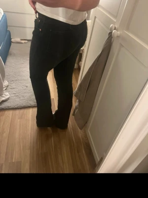 Svarta bootcut jeans - Säljer ett par svarta bootcut jeans med klassisk femficksmodell och normal midja. Jeansen har en snygg passform som sitter tajt över låren och släpper ut vid vaden. Perfekta till en enkel topp eller hoodie.
