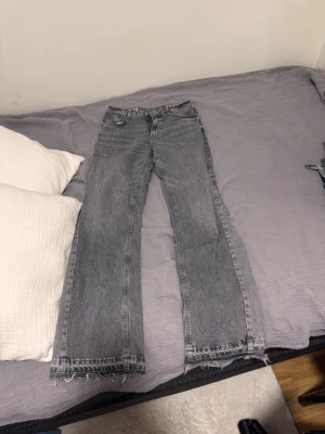 Grå raka jeans från ZARA - Snygga grå jeans från ZARA i rak modell med råa, fransiga benslut. Jeansen har klassisk femficksdesign och är tillverkade i denim. Perfekta för en avslappnad och trendig look.