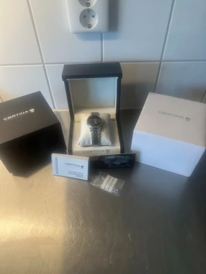 Certina ds-1 automatisk klocka powermatic 80 - Säljer nu min mycket fina automatiska Certina ds-1 Powermatic 80 med svart urtavla. Klockan fungerar lika bra till vardags som vid mer uppklädda tillfällen och som passar till allt.   Klockan går utmärkt med det pålitliga powermatic 80 urverket. Den är i väldigt gott använt skick med normala mindre bruksspår. Klockan är full set så alla tillbehör medföljer som bilderna i annonsen visar.   Nypris: 8900 kr Hör av er vid frågor eller funderingar så löser vi en schysst affär!