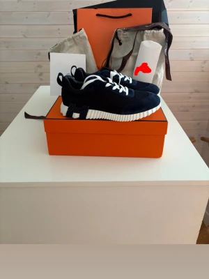 Mörkblå sneakers med vit sula - Snygga mörkblå sneakers med chunky vit sula och vita skosnören. Ovandelen är i en mix av mocka och textil, vilket ger en modern och sportig look. Skorna har låg profil och coola detaljer på hälen. Perfekta för dig som vill sticka ut.