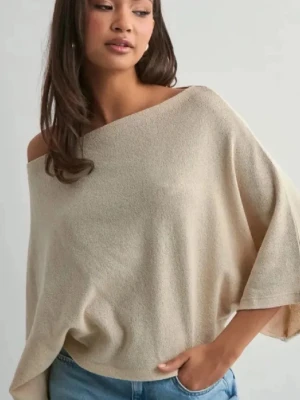 Beige off shoulder ponchotröja - Säljer en beige ponchotröja med off shoulder-design och vida ärmar. Tröjan har en avslappnad passform och är gjord i ett mjukt, stickat material som ger en chill och trendig vibe. Perfekt att styla med jeans för en casual look.