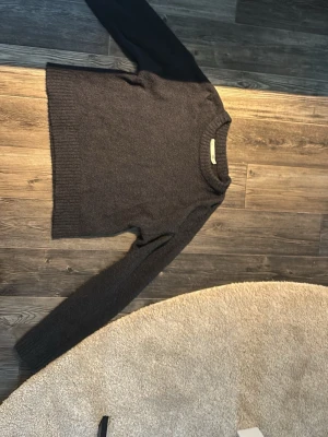 Mörkgrå stickad tröja - Mysig mörkgrå stickad tröja med rund halsringning och långa ärmar. Tröjan har en enkel, klassisk design med ribbstickade muddar vid ärmslut och nederkant. Perfekt för lager på lager och passar till det mesta i garderoben. Lite av den kortare sidan runt magen 