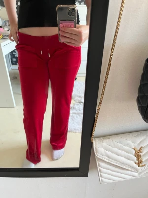 Röda juicybyxor - Säljer ett par snygga röda juicybyxor i mjuk velour. Byxorna har stora fickor framtill och baktill, använda 1 gång.