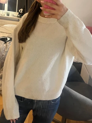 Vit oversized stickad tröja - Mysig vit stickad tröja med oversized passform och rund hals. Tröjan har långa ärmar och ribbade muddar vid ärmslut och nederkant. Perfekt för lager på lager och enkel att matcha med jeans eller kjol.