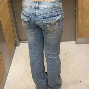 Blå jeans med broderade fickor - Snygga blå jeans med låg midja och broderade detaljer på bakfickorna. De är i storlek 38 men passar även mig som har 36 i vanliga fall. Dom är knappt använda och är i mycket bra skick