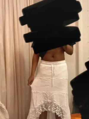 Vit långkjol med spetsdetaljer - Säljer en vit långkjol med snygga spetsdetaljer längst ner och volangkant. 